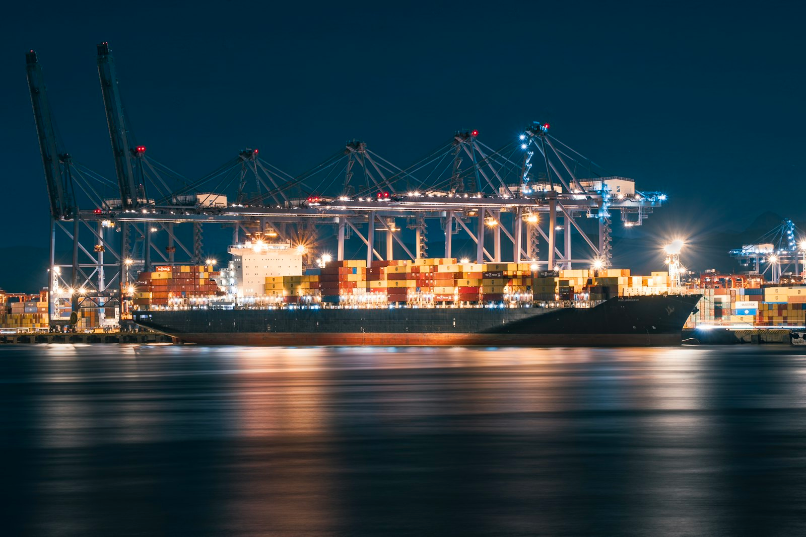 Cargo ship and port cranes lit up at night in Shenzhen, China